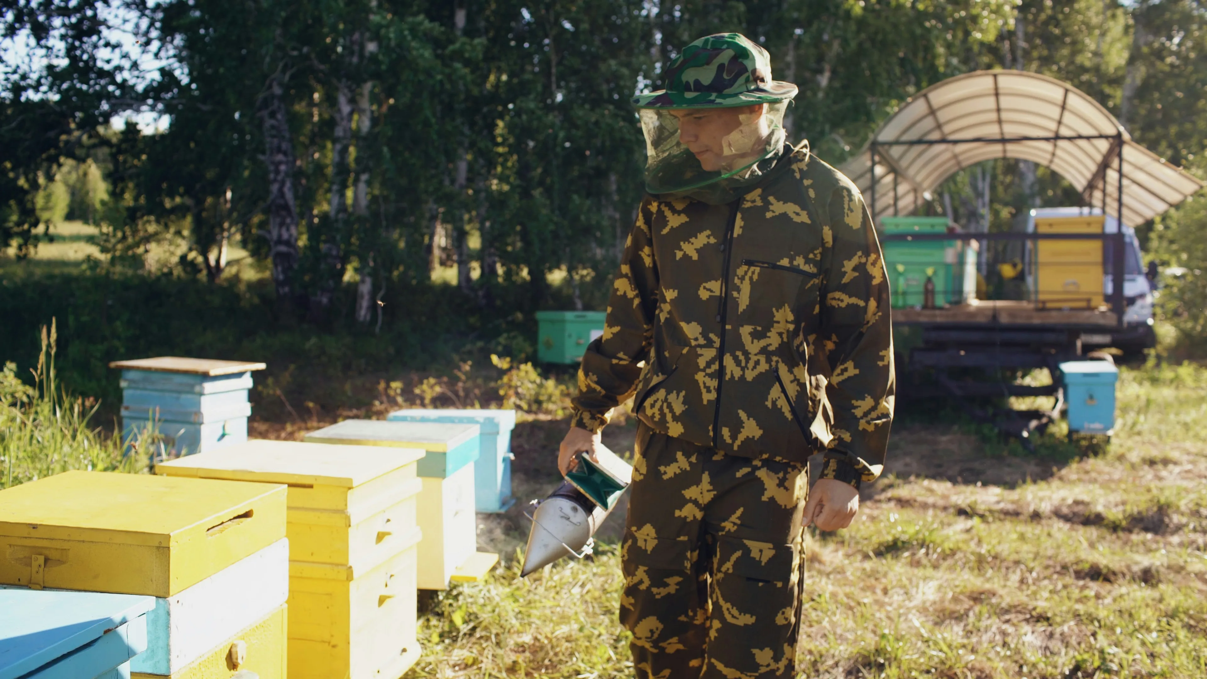 Beekeeper in protective gear tending to beehives outdoors